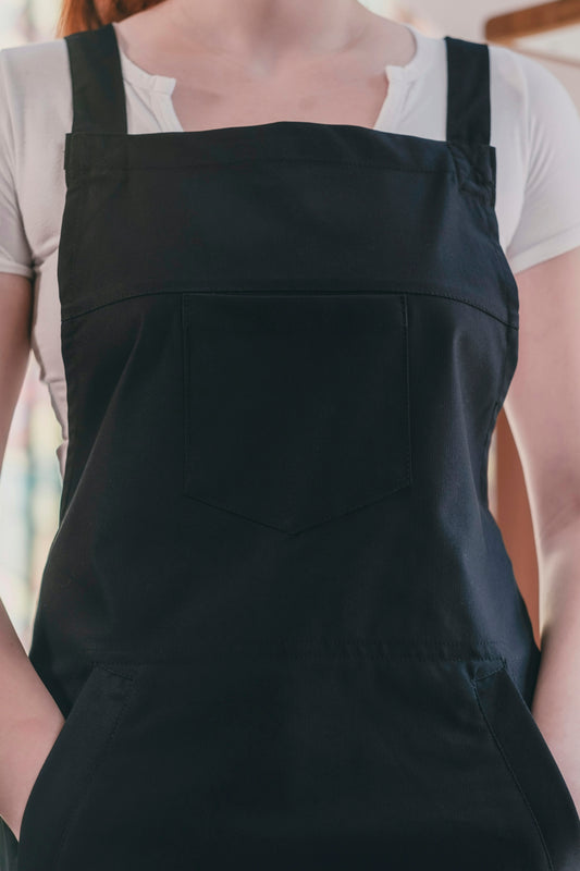 A woman wearing a black apron and a white t - shirt